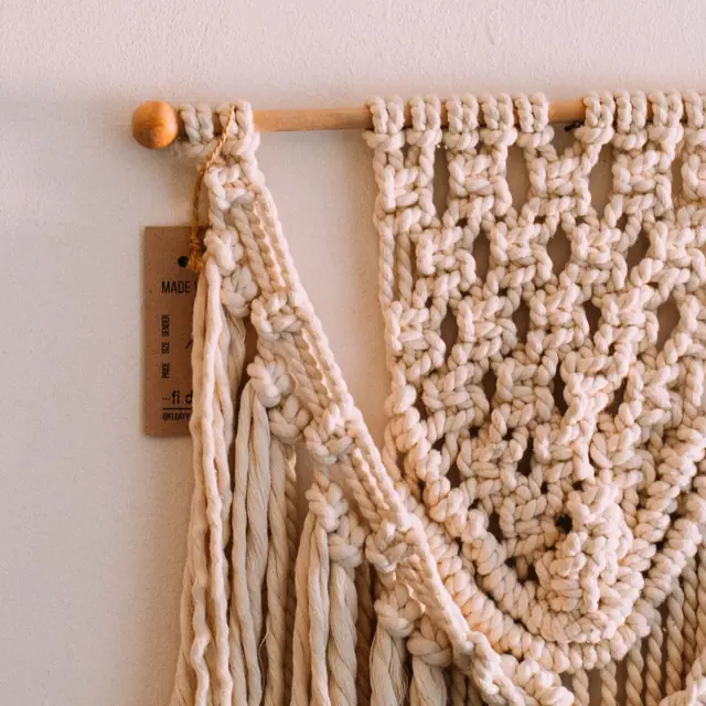 Cream cotton macramé wall hanging on a wooden dowel