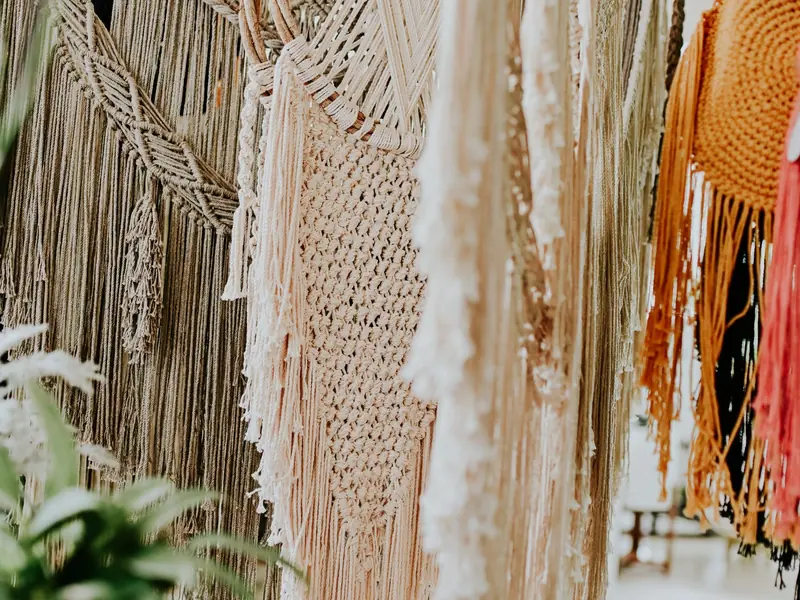 Hanging macramé strands in cream and ochre with green plants