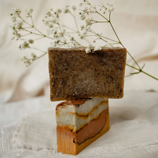 Two stacked handmade soap bars, one oat-flecked and one layered with honey tones