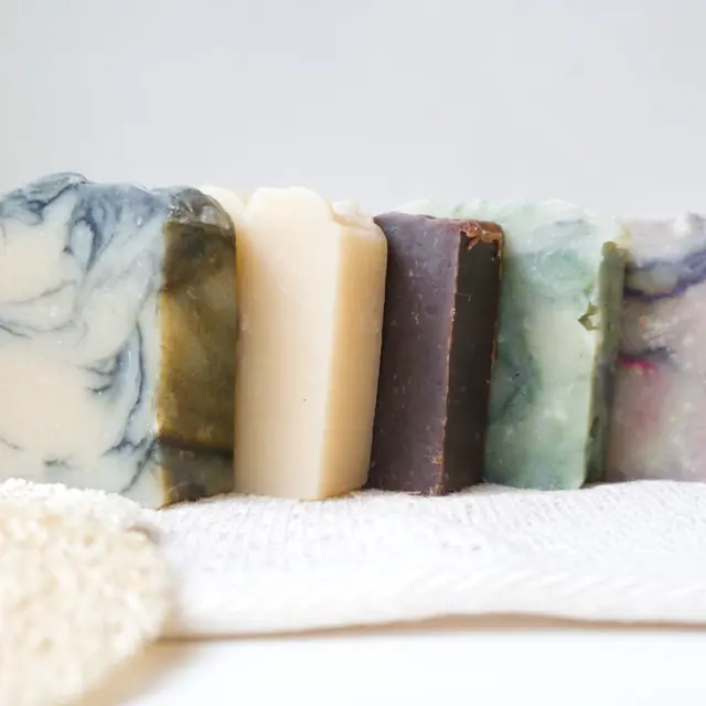 Five-bar row of handmade cold-process soaps, marbled and plain