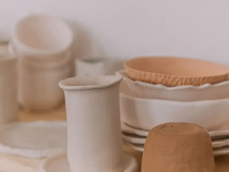 Cream stoneware cups, bowls and jugs on a studio shelf
