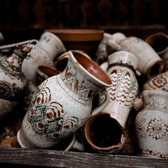 A pile of hand-painted ceramic jugs and vases with brown patterns
